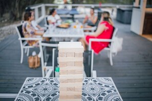 A wooden block tower on a table with a patterned tablecloth, set on a deck with outdoor seating.
