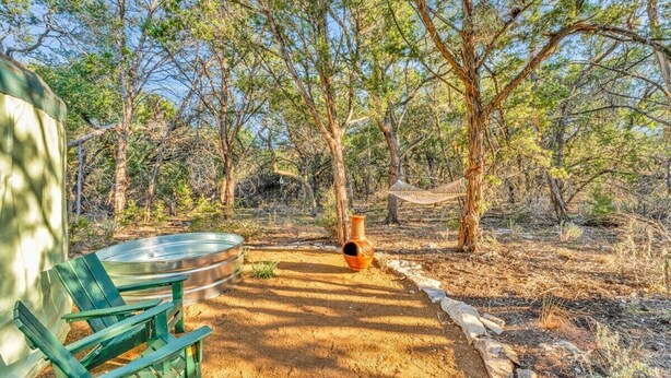 A rustic outdoor setting with a hammock, a metal basin, and a green chair. - Romantic Yurt | Cowboy Pool | Hot Tub| Near Wine (Driftwood)