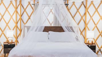 Een bed met hemelbed in een tentachtige constructie met een lattenwand.
