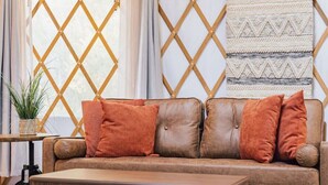 A cozy interior with a leather sofa, a wooden coffee table, and a patterned wall hanging. - Romantic Yurt | Cowboy Pool | Hot Tub| Near Wine (Driftwood)