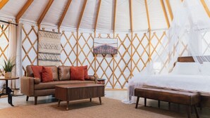 A tented accommodation with a sofa, a bed with a canopy, and a wall-mounted picture. - Romantic Yurt | Cowboy Pool | Hot Tub| Near Wine (Driftwood)