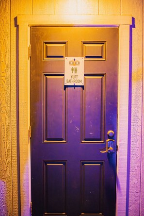Puerta con un letrero que indica baño de yurtas.