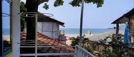 Una propiedad frente a la playa con balcón que da al mar, un árbol que proporciona sombra y vistas a la playa.