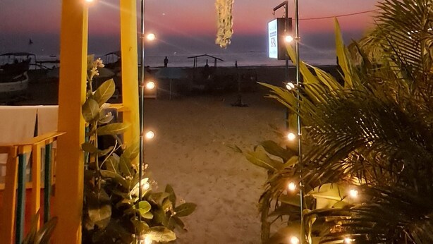 A beach entrance with a wooden archway, string lights, and a sign. - Columbus goa  (Canacona)