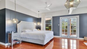 A bedroom with a large bed, a nightstand, a ceiling fan, and a view through the door.