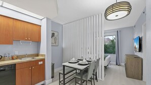 Cuina moderna amb armaris de fusta, un rentaplats i zona de menjador amb taula preparada per a quatre.
