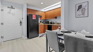 Cuina moderna amb armaris de fusta, un refrigerador negre i zona de menjador amb taula preparada per a dues persones.