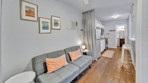 Un salon moderne avec un canapé gris, un ventilateur de plafond et des tableaux encadrés accrochés au mur.