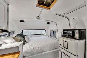 Een knus interieur met een stapelbed, een magnetron en een klein raam.