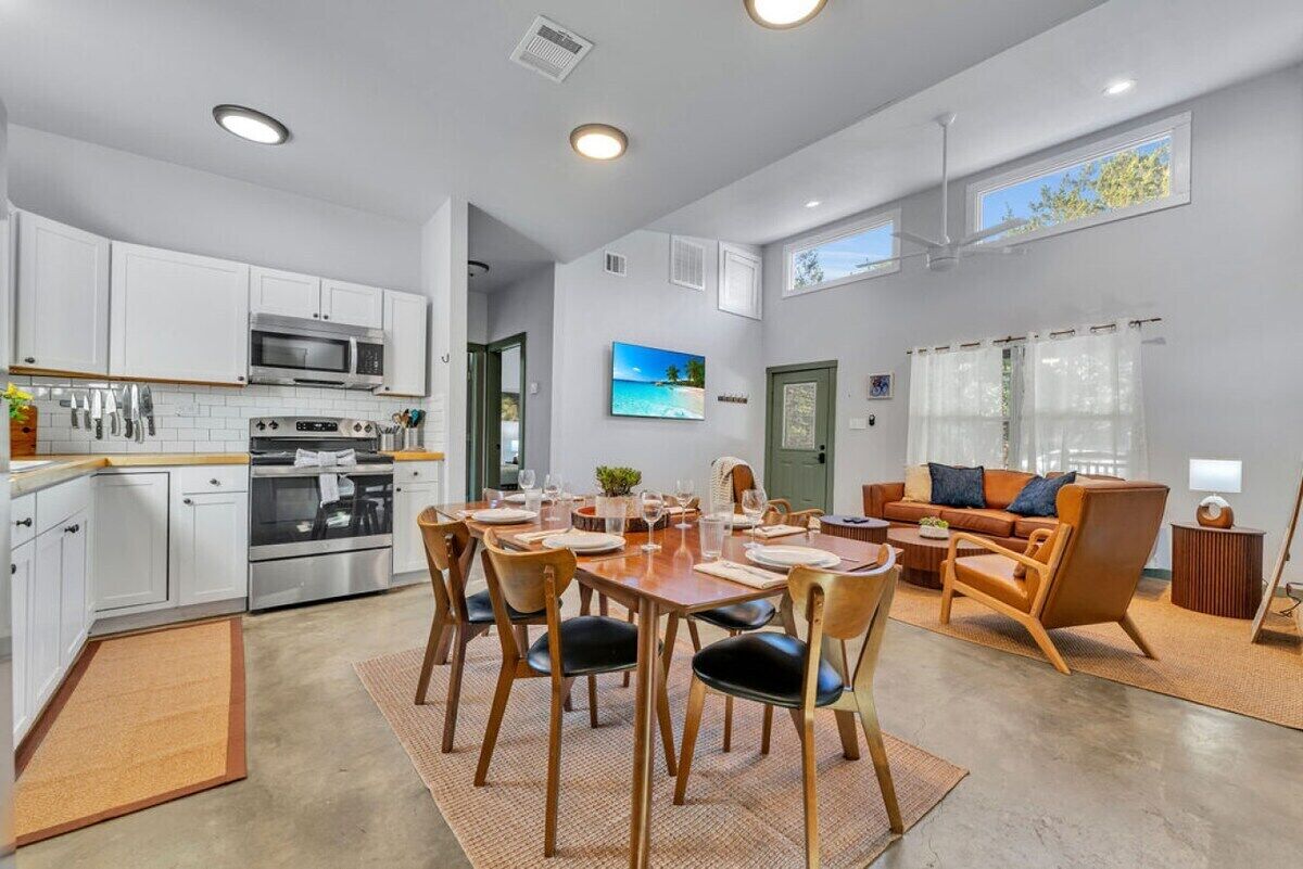 A modern kitchen with white cabinets, a microwave, and a dining area with wooden chairs and a table set for four.