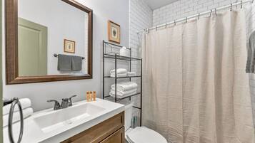Ein Badezimmer mit Waschbecken, Toilette, Duschvorhang und Handtuchhalter.