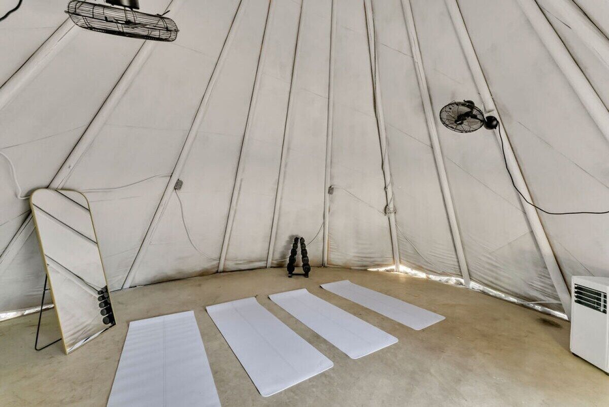 A tent-like structure with a fan and a heater, and three mats laid out on the floor.