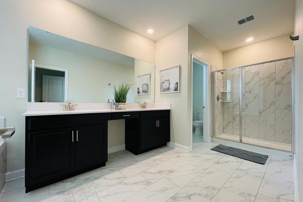 Un baño moderno con tocador doble, un espejo grande y una ducha a pie con azulejos de mármol.