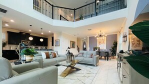 A spacious living area with a high ceiling, a dining area, and a kitchen. - New 5BR/5BA home w/ private pool & hot tub, minutes to DIsney.  Sleeps up to 15. (Kissimmee)