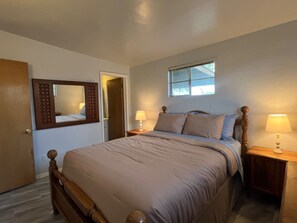 A bedroom with a bed, two bedside tables with lamps, a window, and a door. - Affordable Family Home Perfect for Monthly Stays! (Tucson)