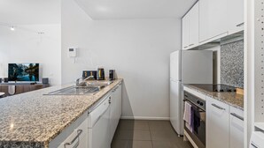 A modern kitchen with white cabinets, granite countertops, stainless steel appliances, and a built-in oven. - Chic Inner-city Stay With Balcony (Melbourne)