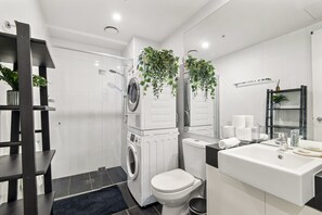 Ein modernes Badezimmer mit Waschmaschine, Toilette und Waschbecken.
