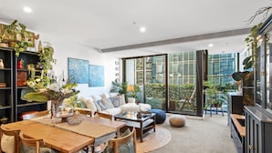 A modern living room with a dining area, large windows, and indoor plants. - Chic 2-bed Apartment With Balcony in Southbank (Melbourne)