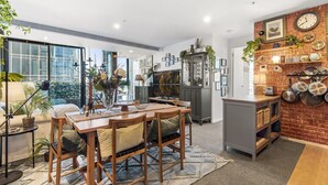 A modern kitchen with a dining area, large windows, and a brick accent wall. - Chic 2-bed Apartment With Balcony in Southbank (Melbourne)