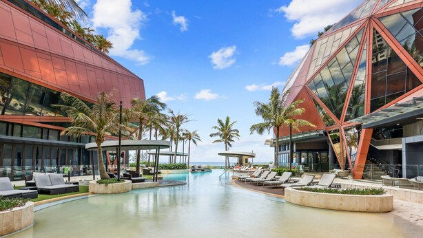 A modern resort with a central swimming pool, lounge areas, and palm trees. - Jewel Luxury Beachside 2-bed With Water View (Gold Coast)