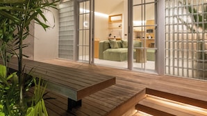 A modern house with a wooden deck, large glass doors, and indoor lighting.