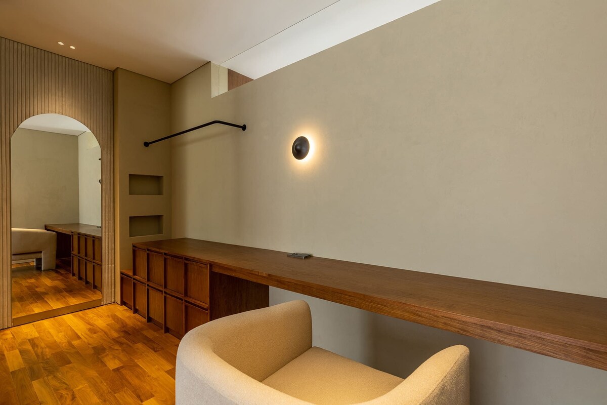 A modern interior with a wooden bench, a wall-mounted light, and a built-in shelving unit.