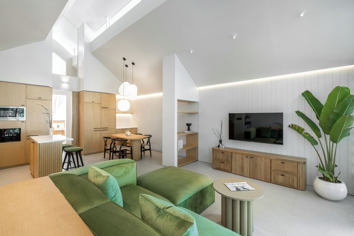 Una sala de estar moderna con un sofá verde, un comedor y una cocina.