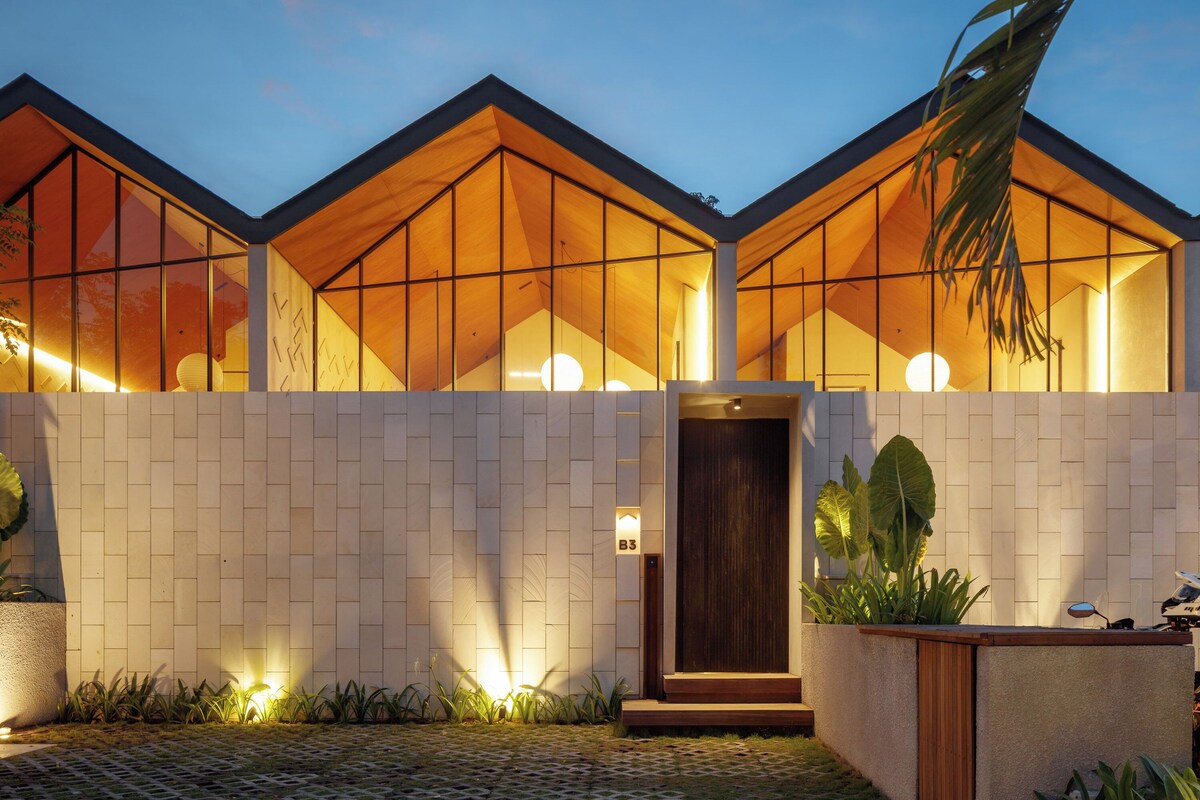 A modern building with large glass windows, a wooden facade, and a well-lit entrance.