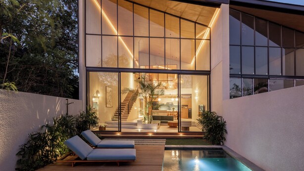 A modern house with large glass windows, a pool, and a wooden deck.