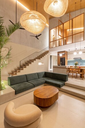 A modern interior with a sectional sofa, a round wooden coffee table, and a staircase leading to an upper level.