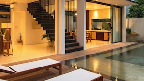 A modern two-story house with a balcony, a staircase, and a pool area.