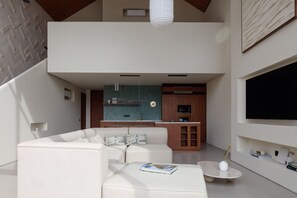 A modern living room with a sectional sofa, a coffee table, and a flat-screen TV mounted on the wall.