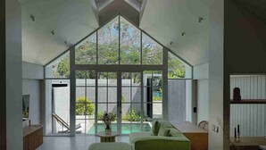 A spacious living area with a large glass window, a pool, and a modern interior design.