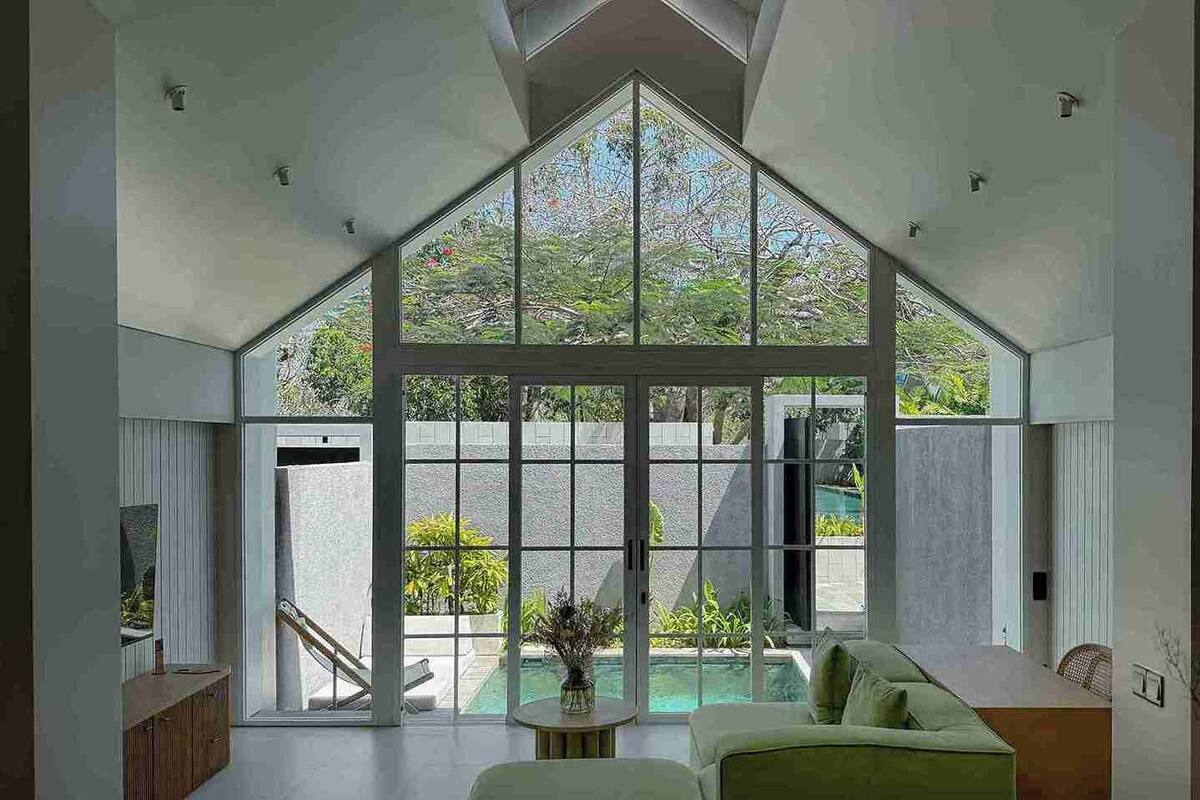 A spacious living area with a large glass window, a pool, and a modern interior design.
