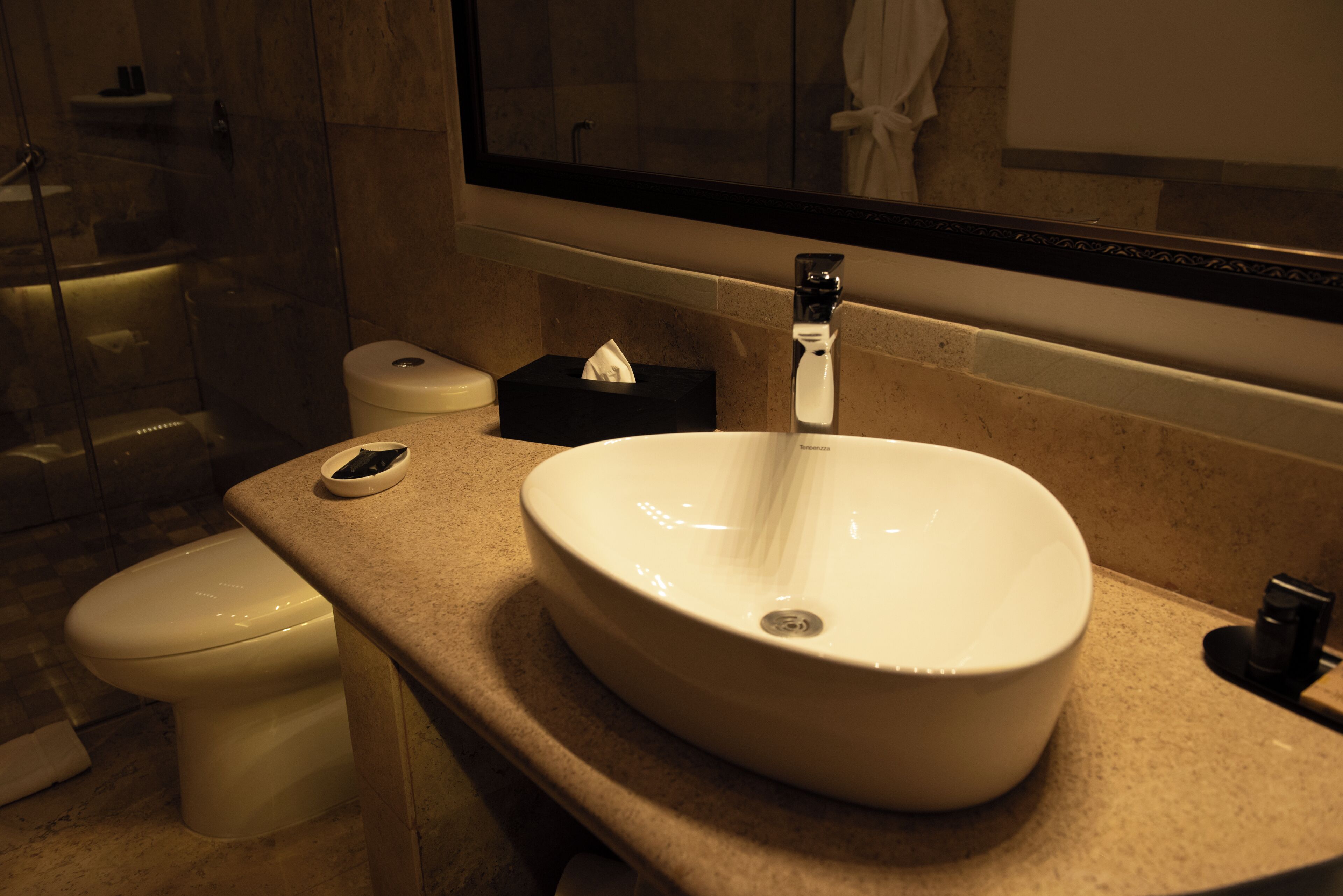 Une salle de bain avec un lavabo blanc, des toilettes, un miroir et un porte-serviettes.