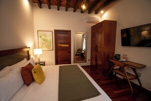 Habitación de hotel con cama, escritorio, silla, televisor y armario.