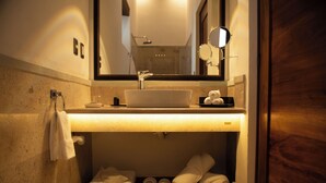 A bathroom with a sink, mirror, towel rack, and a shelf with towels and shoes. - Mirtala Hotel Boutique  (Guanajuato)