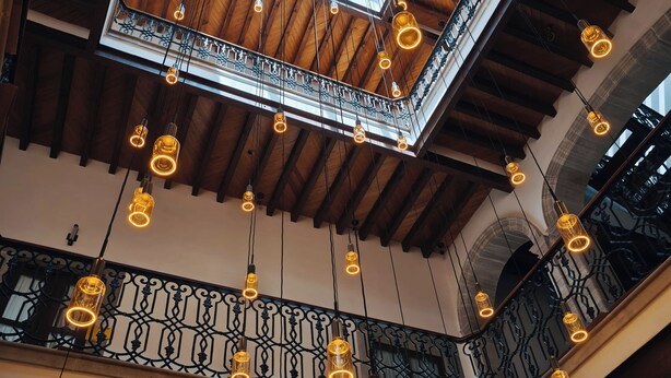 A high-ceilinged interior with exposed wooden beams, a skylight, and multiple hanging pendant lights. - Mirtala Hotel Boutique  (Guanajuato)