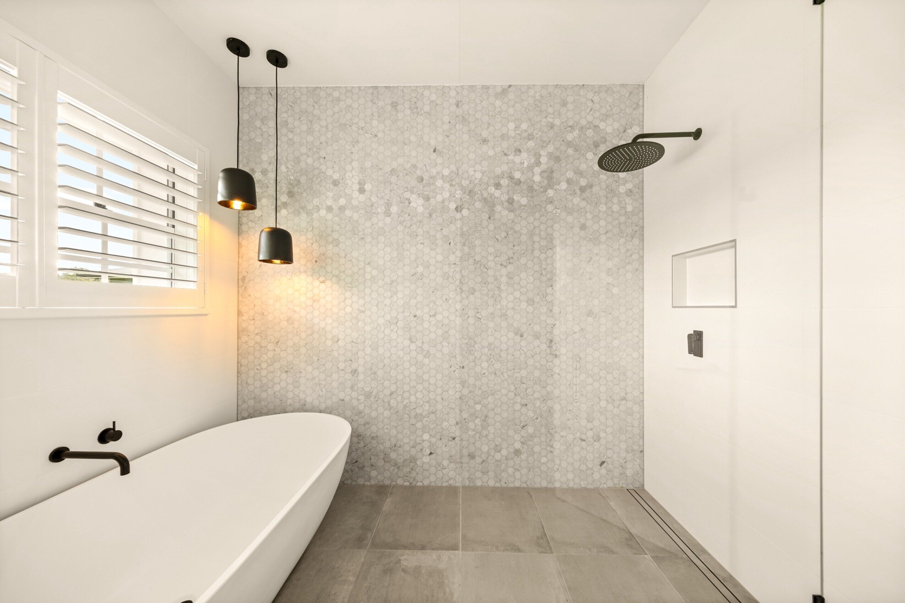 A modern bathroom with a freestanding bathtub, a showerhead, and pendant lighting.