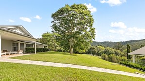 Ein Haus mit einer überdachten Veranda, einem Rasen und einem großen Baum.