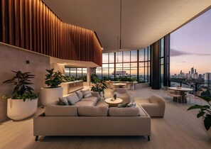 A modern rooftop lounge with a sofa, chairs, and a dining area, featuring large windows and potted plants. - Elegant 2-bed Broadbeach Hotel With Ocean View (Gold Coast)