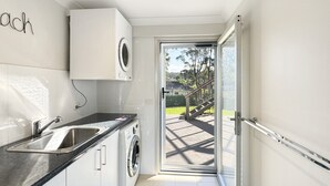 A modern kitchen with a built-in washing machine, a sink, and a countertop. - Spacious Beach Studio With Alfresco Dining (Surf Beach)