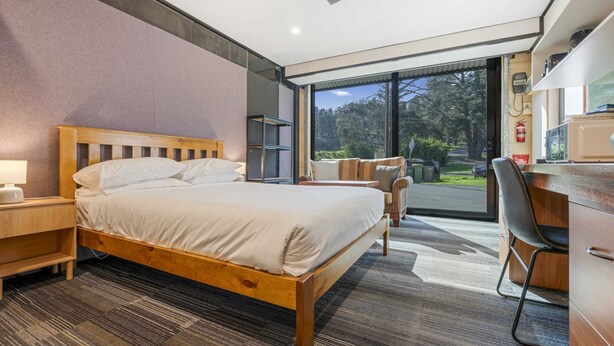 Une chambre d’hôtel moderne avec un lit en bois, un bureau et une vue sur l’extérieur.