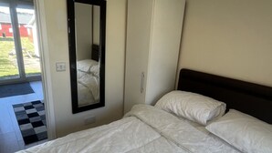 Un dormitorio con cama, espejo y vista a un edificio rojo.