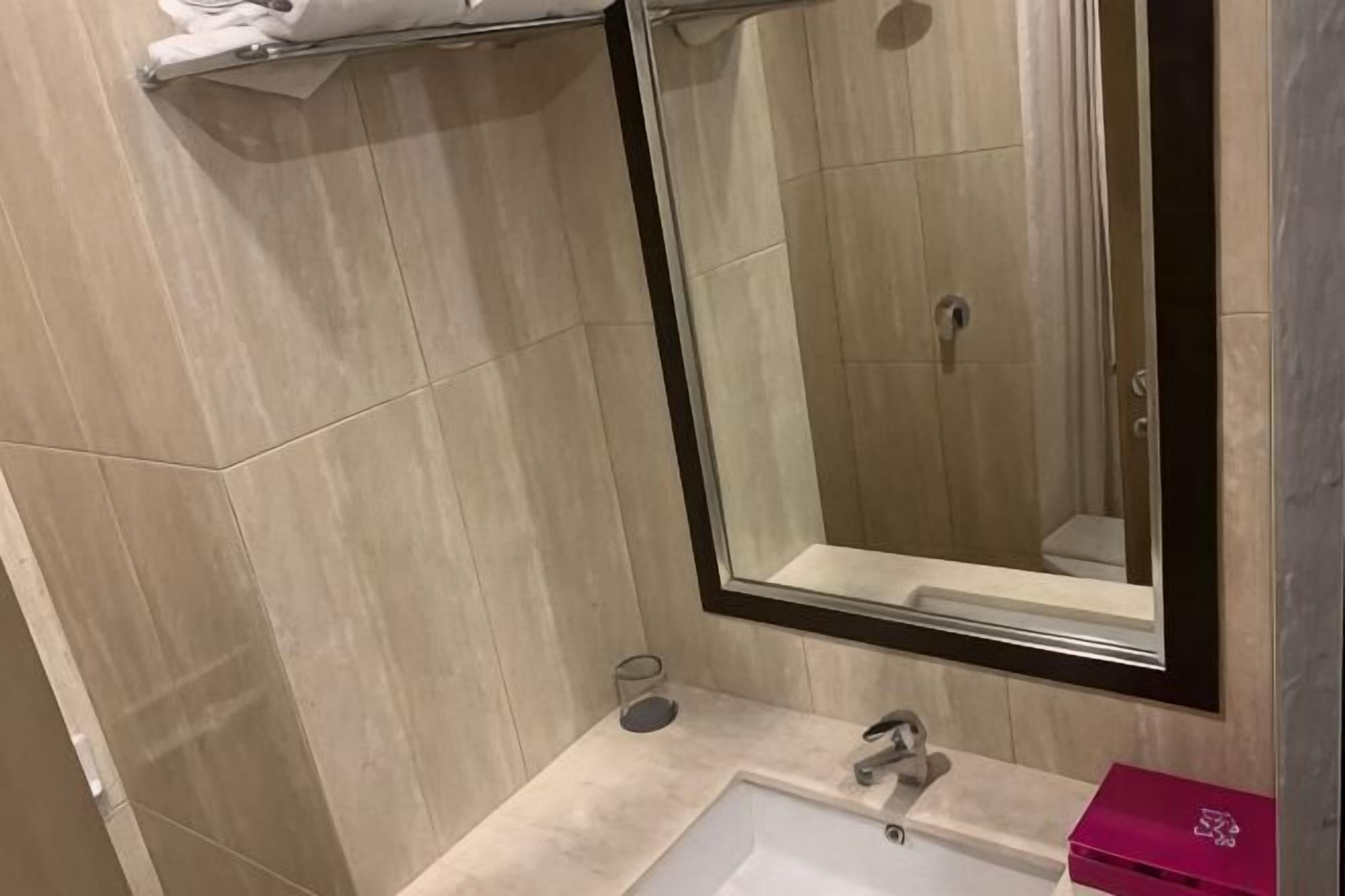 Un baño con ducha, lavamanos y espejo.