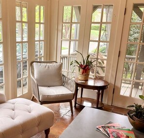 Une pièce comprenant un fauteuil en osier, un pouf rembourré et une petite table sur laquelle se trouve un panier rempli de plantes.