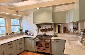 A kitchen with light green cabinets, a stove, and a sink.
