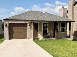 A single-story house with a garage, a front porch, and a well-maintained lawn. - New Waterfront Home: Enjoy Lake LBJ Water Views From Every Bedroom | Luxury (Granite Shoals)