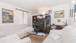 Un salon avec un canapé, une table basse, un téléviseur et une bibliothèque.