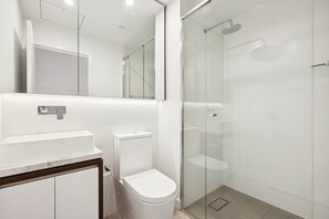 A modern bathroom with a toilet, sink, and glass-enclosed shower.